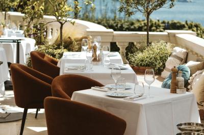 Miniature Location salle Beaulieu-sur-Mer (Alpes-Maritimes) - Circé Restaurant #5 Un homme souriant partage un repas en terrasse avec d'autres personnes, entouré de plats variés et d'un décor extérieur.