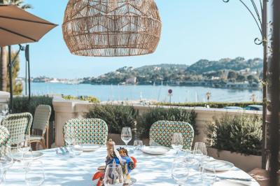 Miniature Location salle Beaulieu-sur-Mer (Alpes-Maritimes) - Circé Restaurant #3 Un homme souriant partage un repas en terrasse avec d'autres personnes, entouré de plats variés et d'un décor extérieur.