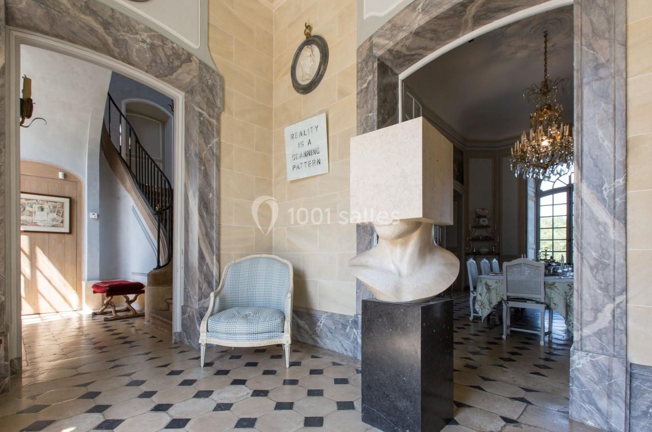 Intérieur élégant avec sol en carreaux, sculpture moderne, chaise tressée, escalier et salle à manger ornée d'un lustre.