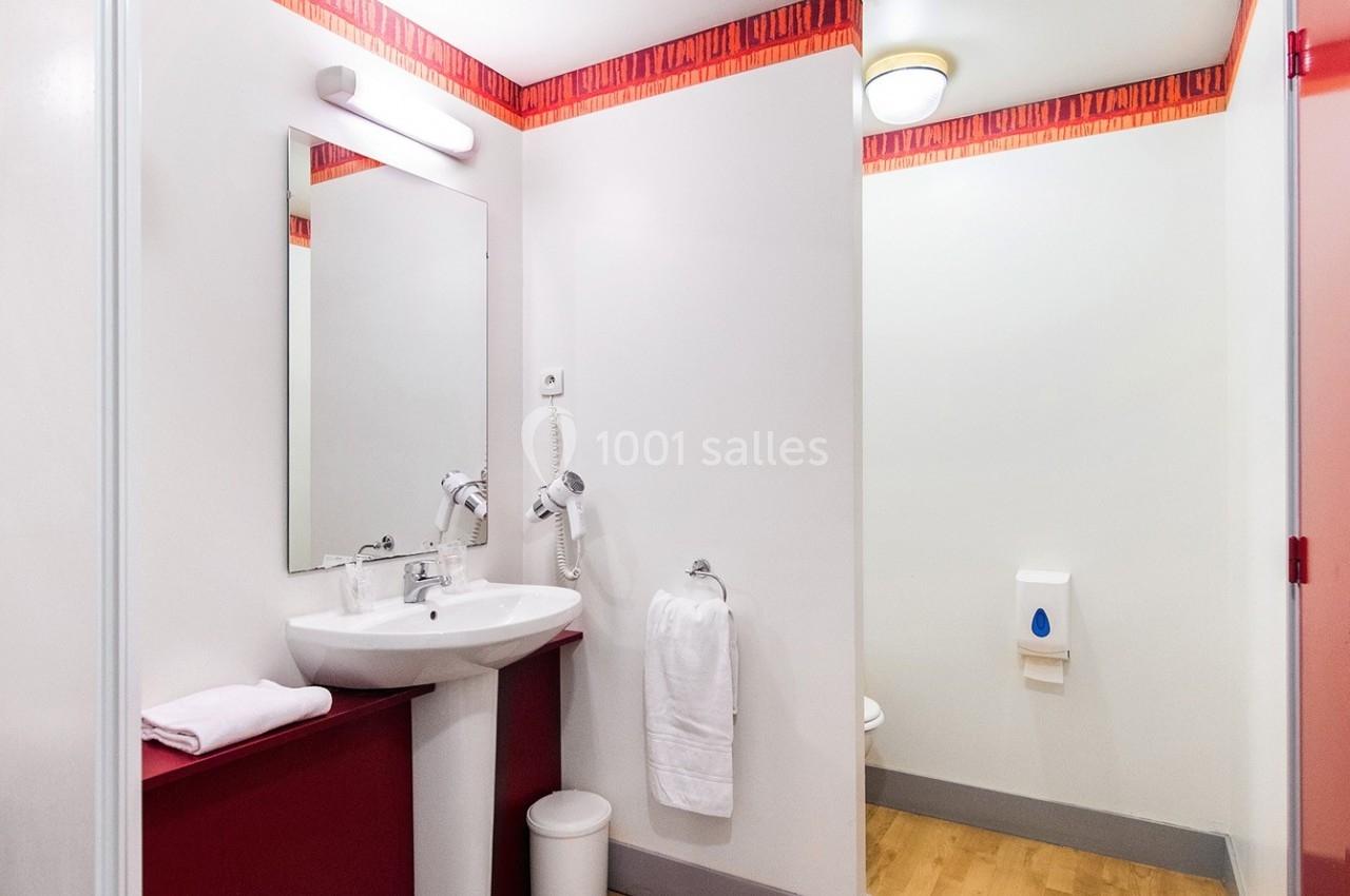 Salle de bain avec lavabo, miroir, serviette suspendue, sol en bois clair et éclairage au plafond.