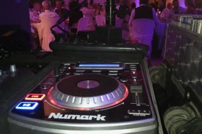 Salle de réception décorée avec des tables dressées et un plan rapproché d'une console de mixage audio.