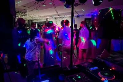 Salle de réception décorée avec des tables dressées et un plan rapproché d'une console de mixage audio.