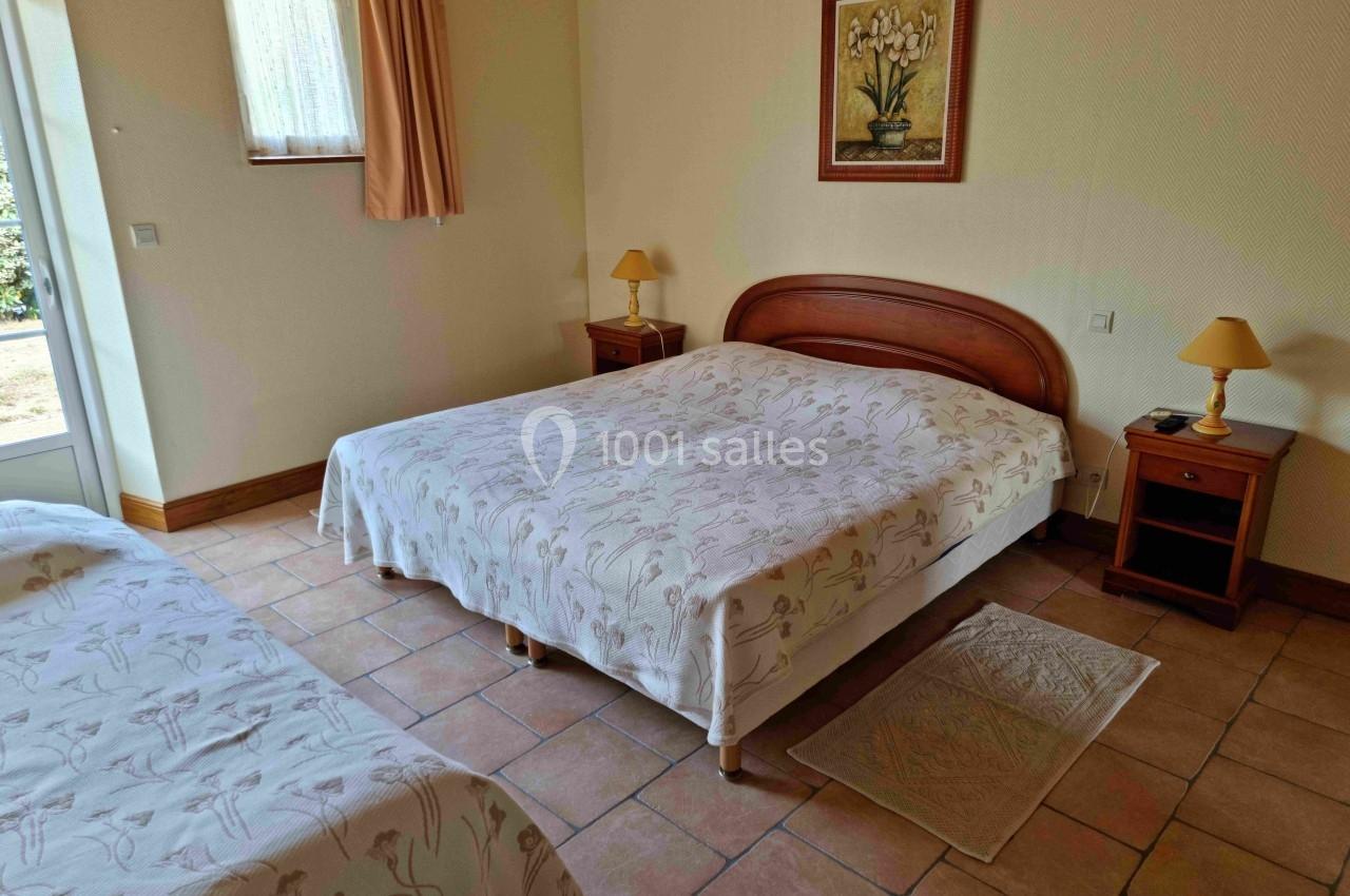 Chambre avec un lit double, un lit simple, des tables de chevet, une fenêtre et un sol en carrelage.