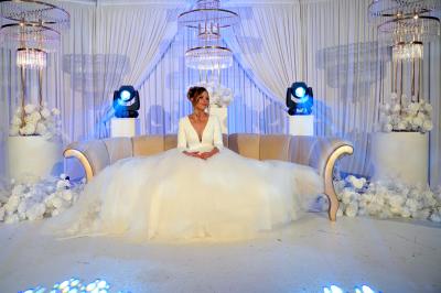 Façade d'un bâtiment moderne éclairé de nuit, avec des plantes et un panneau ’La Scène’ visible.