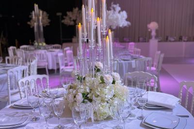 Façade d'un bâtiment moderne éclairé de nuit, avec des plantes et un panneau ’La Scène’ visible.