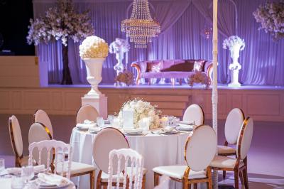 Façade d'un bâtiment moderne éclairé de nuit, avec des plantes et un panneau ’La Scène’ visible.