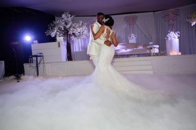 Façade d'un bâtiment moderne éclairé de nuit, avec des plantes et un panneau ’La Scène’ visible.