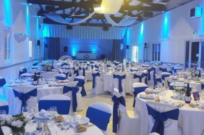 Bâtisse provençale entourée de cyprès et de champs verts, avec des arbres en arrière-plan sous un ciel clair.