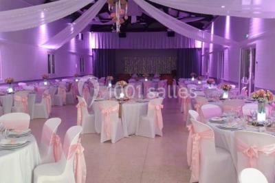 Bâtisse provençale entourée de cyprès et de champs verts, avec des arbres en arrière-plan sous un ciel clair.