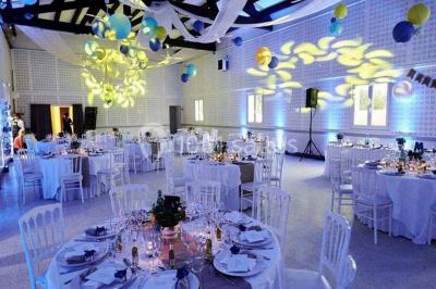 Bâtisse provençale entourée de cyprès et de champs verts, avec des arbres en arrière-plan sous un ciel clair.