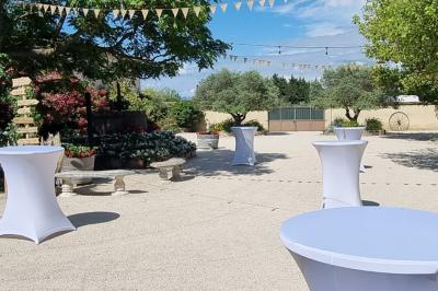 Bâtisse provençale entourée de cyprès et de champs verts, avec des arbres en arrière-plan sous un ciel clair.