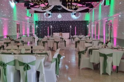 Bâtisse provençale entourée de cyprès et de champs verts, avec des arbres en arrière-plan sous un ciel clair.