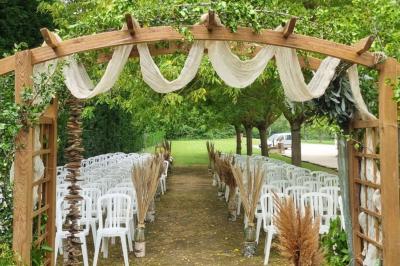 Bâtisse provençale entourée de cyprès et de champs verts, avec des arbres en arrière-plan sous un ciel clair.