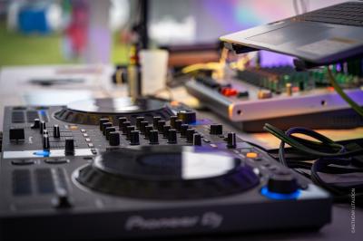 Miniature DJ Mâcon (Saône-et-Loire) - Mjps Sonorisation #3 Poste de DJ avec ordinateur portable affichant un logiciel de mixage, platine et microphone sur une table éclairée en violet.