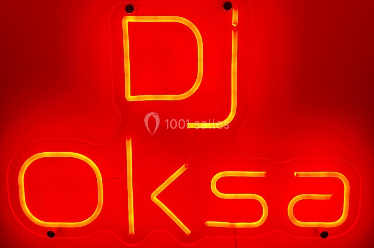Enseigne lumineuse rouge avec le texte ’DJ OKSA’ écrit en lettres jaunes néon.