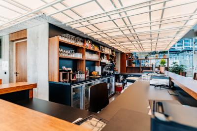 Miniature Location salle Lyon 2 (Rhône) - Lumen #4 Un café moderne avec un comptoir en bois, des tabourets, des clients et des baristas en pleine discussion.