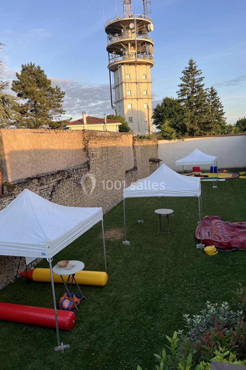 Tentes blanches installées sur une pelouse entourée de murs en pierre, avec une tour en arrière-plan.