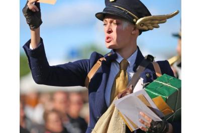 Deux personnes déguisées, l'une en tenue festive excentrique et l'autre en costume de Père Noël, posent devant des sacs…