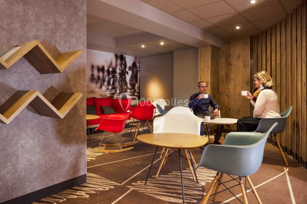 Deux personnes assises dans un espace lounge moderne avec des chaises colorées et une décoration en bois.
