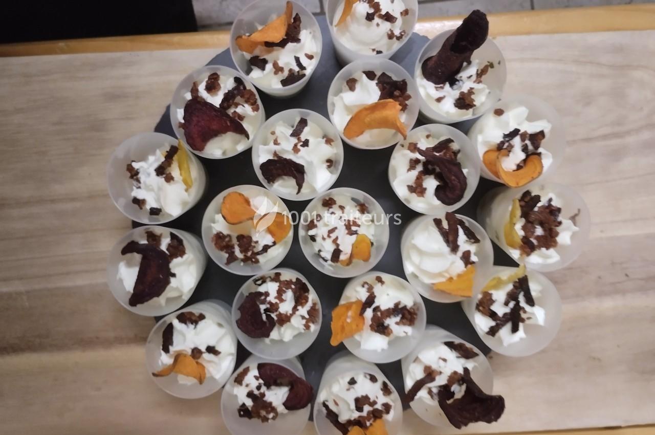Verrines de crème garnies de chips de légumes colorées et éclats croustillants, disposées en cercle sur une table.