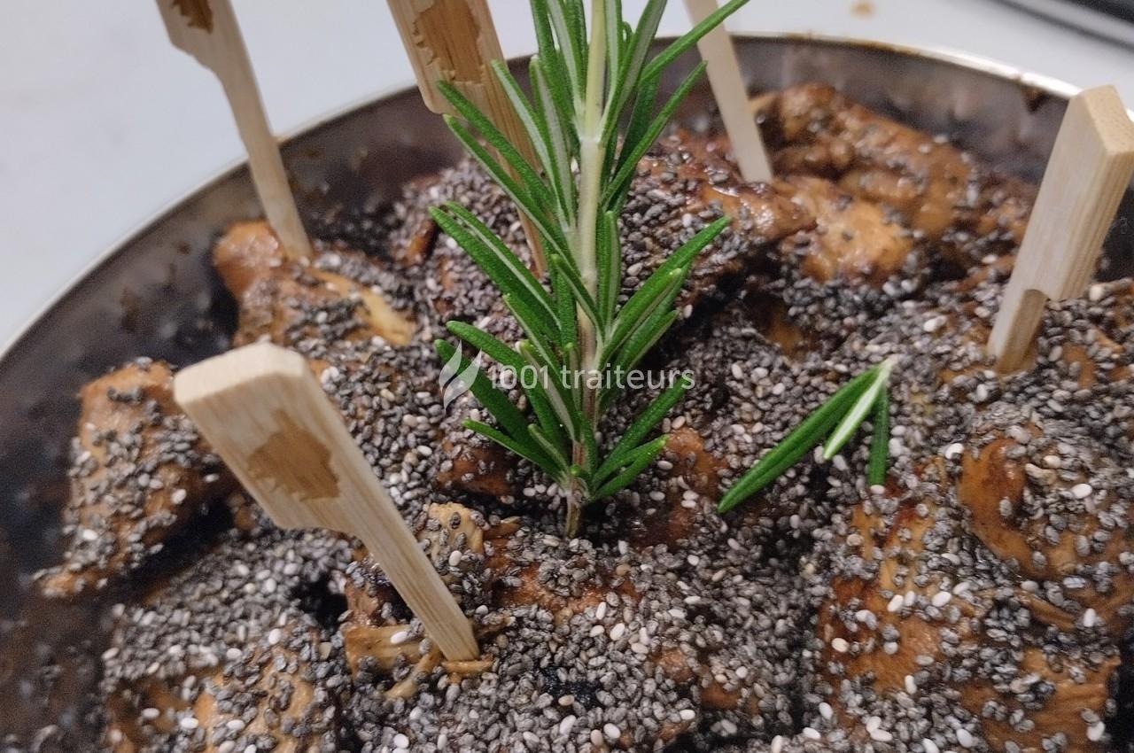 Morceaux de viande grillée garnis de graines de chia, présentés avec des piques en bois et une branche de romarin.