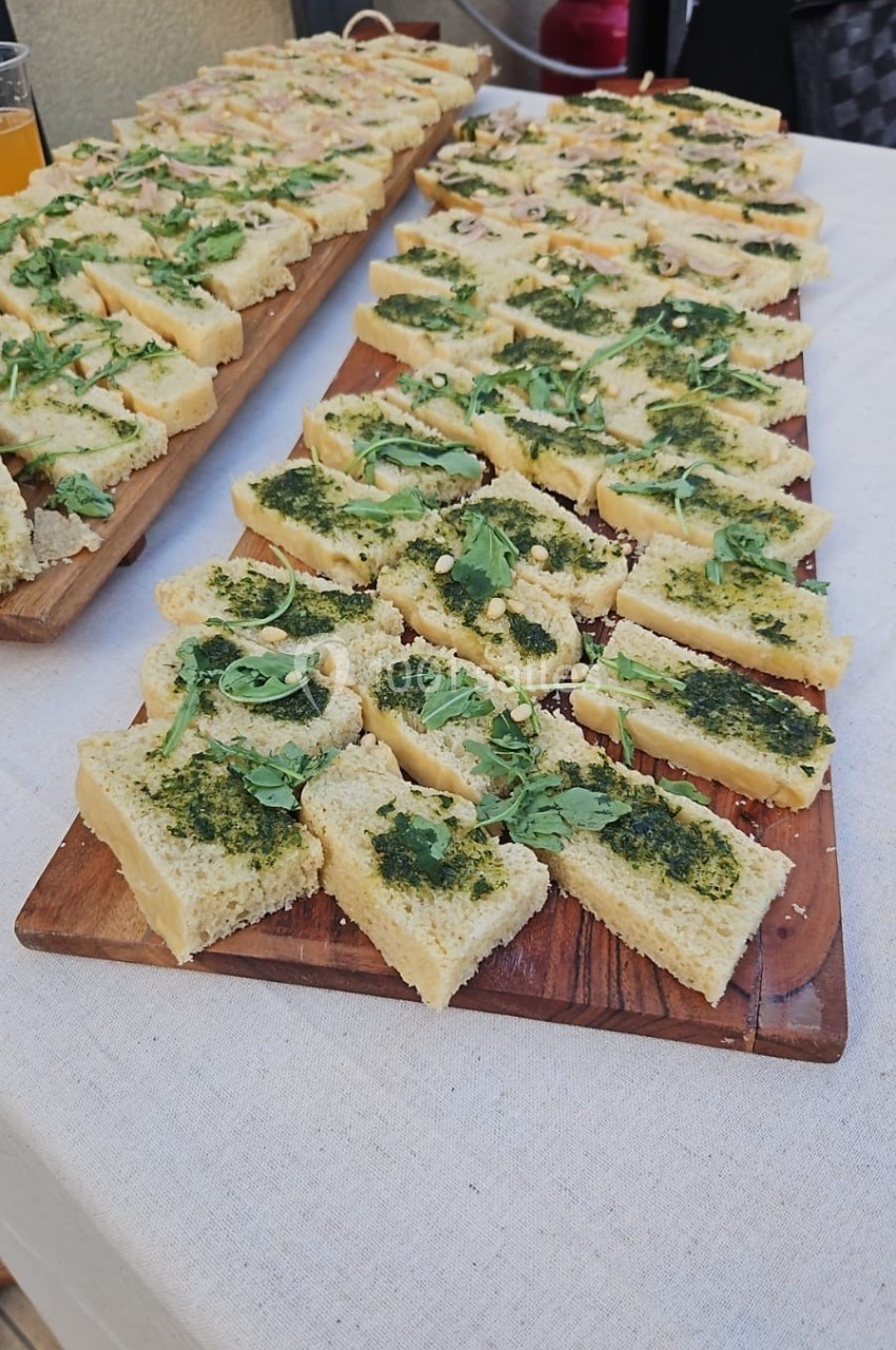 Tranches de pain garnies de pesto et herbes fraîches, disposées sur des planches en bois.