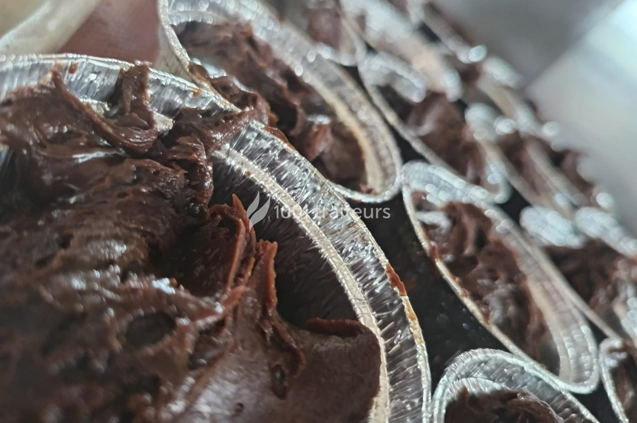 Gros plan sur des moules en aluminium remplis de pâte au chocolat prête à être cuite.