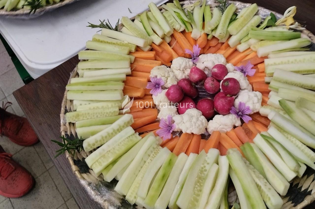 Plateau de légumes frais disposés en cercle avec concombres, carottes, radis, chou-fleur et fleurs comestibles.