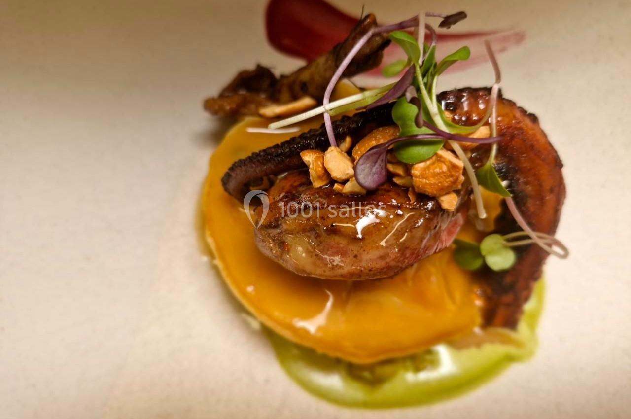 Assiette gastronomique avec un morceau de poulpe grillé, purée colorée, pousses fraîches et éclats croquants.