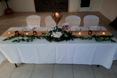 Salle de réception avec tables rondes dressées, nappes blanches, chemins de table en dentelle et décoration élégante.