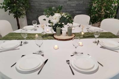 Salle de réception avec tables rondes dressées, nappes blanches, chemins de table en dentelle et décoration élégante.