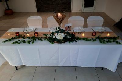 Salle de réception décorée avec des tables rondes dressées, nappes blanches et chaises ornées de nœuds beige.