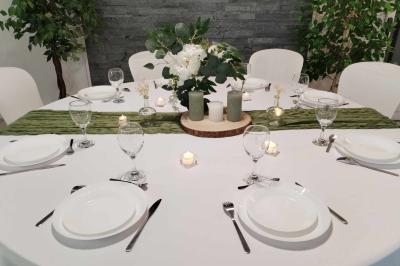Salle de réception décorée avec des tables rondes dressées, nappes blanches et chaises ornées de nœuds beige.