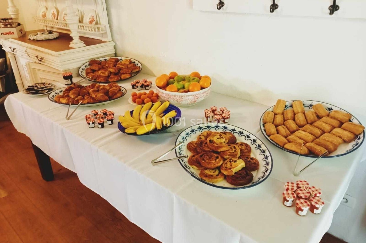 Buffet de petit-déjeuner avec viennoiseries, fruits, confitures en portions individuelles et autres mets sur une table…