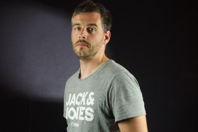 Chaussures blanches à talons posées sur un sol en bois, près d'une robe en tissu léger.