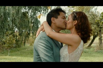 Chaussures blanches à talons posées sur un sol en bois, près d'une robe en tissu léger.