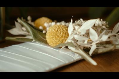 Chaussures blanches à talons posées sur un sol en bois, près d'une robe en tissu léger.