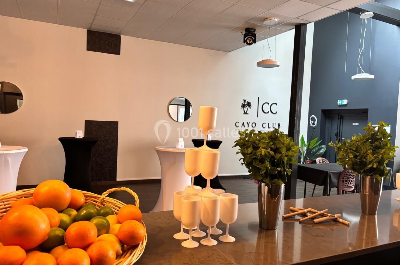 Corbeille de fruits, verres blancs empilés et plantes décoratives sur un comptoir dans une salle moderne.