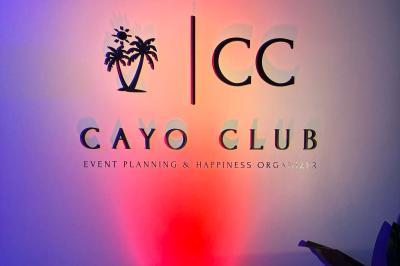 Logo circulaire du Cayo Club avec des palmiers, un soleil et le texte ’Event Planning & Happiness Organizer’.