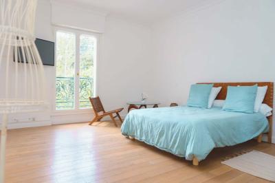 Salle de bain luxueuse avec baignoire en marbre, double vasque, miroirs, et fenêtre donnant sur un jardin.