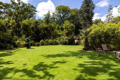 Salle de bain luxueuse avec baignoire en marbre, double vasque, miroirs, et fenêtre donnant sur un jardin.