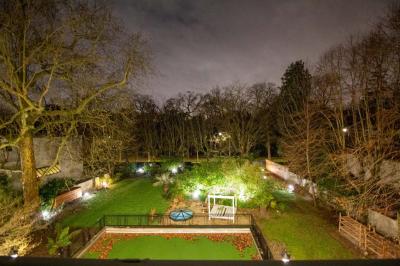 Salle de bain luxueuse avec baignoire en marbre, double vasque, miroirs, et fenêtre donnant sur un jardin.