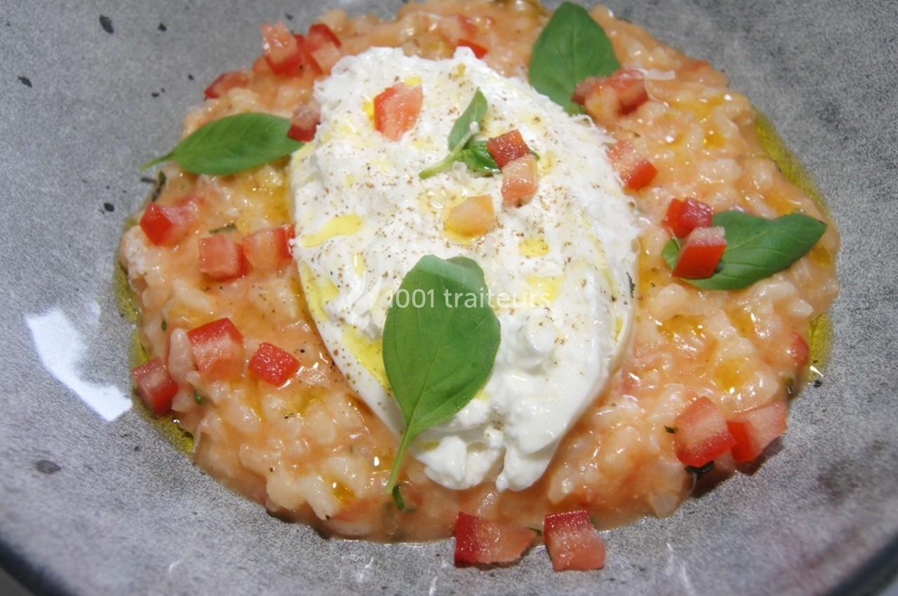 Assiette de risotto crémeux aux tomates, garni de burrata, feuilles de basilic et dés de tomate fraîche.