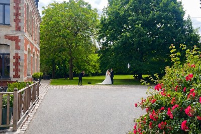 Miniature Location salle Rues-des-Vignes (Nord) - Domaine de Revelon #12 Un couple échange ses vœux sous une arche fleurie lors d'une cérémonie de mariage en plein air, entouré d'invités.