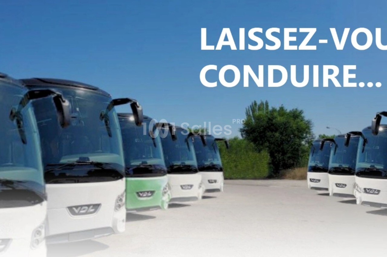 Alignement de plusieurs bus blancs stationnés sur un parking, avec un ciel bleu en arrière-plan.