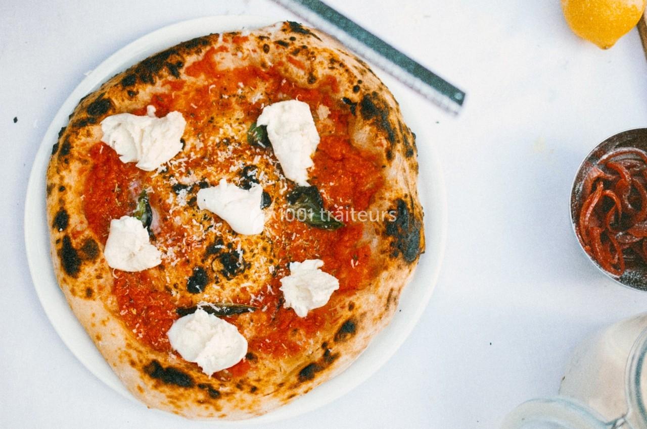 Pizza napolitaine garnie de sauce tomate, mozzarella, basilic et fromage râpé, servie sur une assiette blanche.