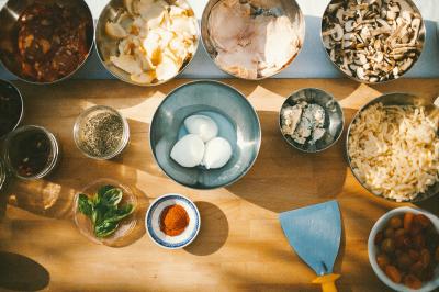 Miniature Traiteur Paris (Paris) - Pizzaiolo Tsogani #11 Un homme retire une pizza du four à l'aide d'une pelle, accompagné d'une femme souriante dans une cuisine moderne.