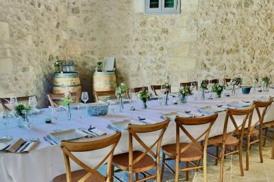 Miniature Location salle Tresses (Gironde) - Domaine de la Rose Blanche #4 Façade d'une maison en pierre avec terrasse ensoleillée, chaises longues et pots de fleurs sur un sol pavé clair.
