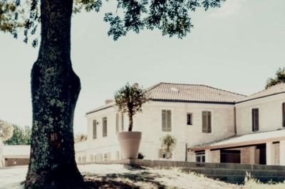 Miniature Location salle Tresses (Gironde) - Domaine de la Rose Blanche #15 Façade d'une maison en pierre avec terrasse ensoleillée, chaises longues et pots de fleurs sur un sol pavé clair.