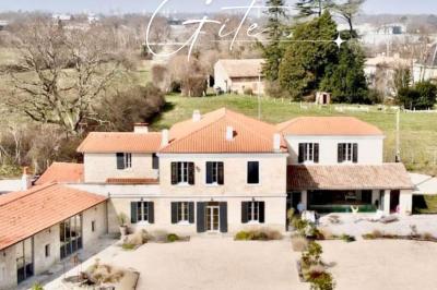 Miniature Location salle Tresses (Gironde) - Domaine de la Rose Blanche #1 Façade d'une maison en pierre avec terrasse ensoleillée, chaises longues et pots de fleurs sur un sol pavé clair.